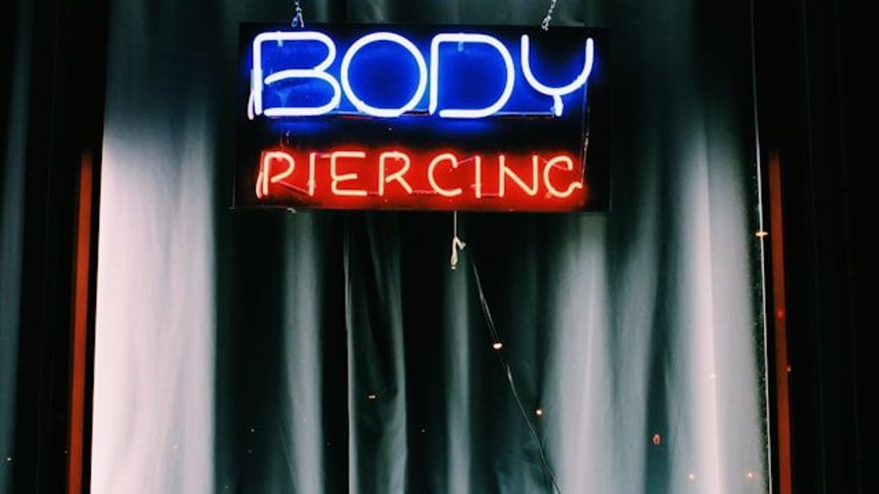 Shot of a neon shop sign saying "body piercing." The word body is blue, and piercing is red.