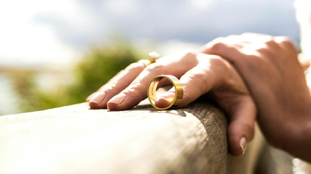 Shot of a pair of hands. A woman's index finger holds a wedding ring.