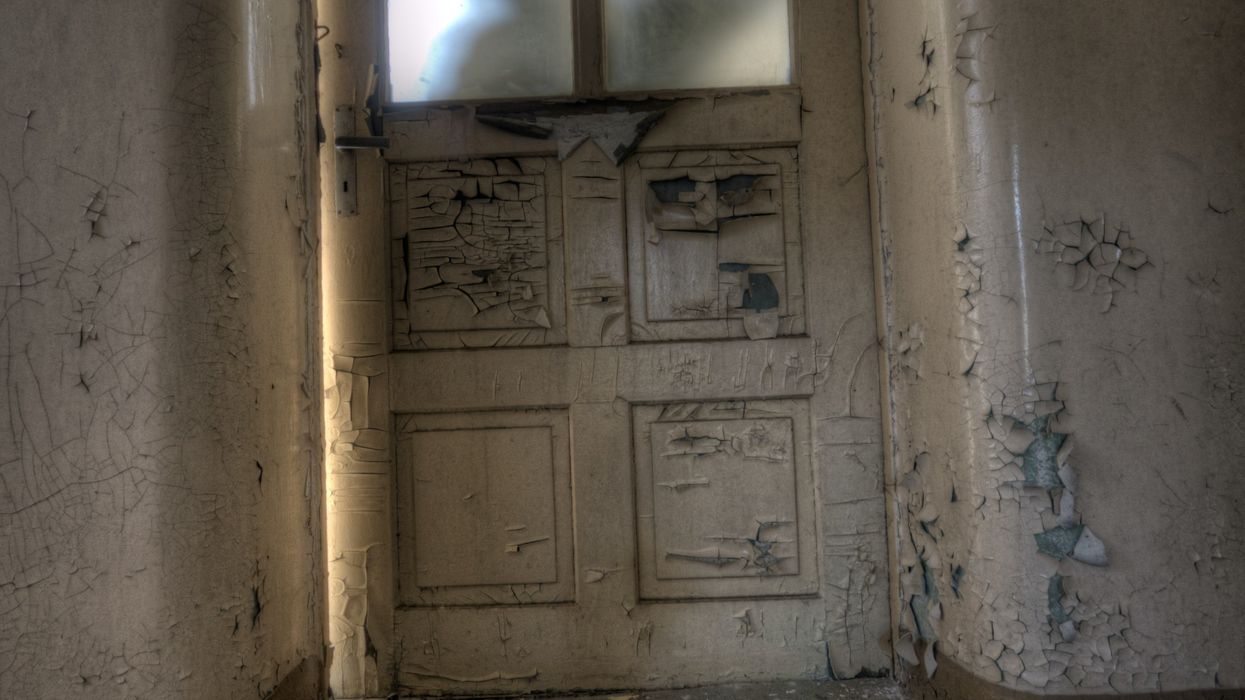 Silhouette of a person trying to break into a room through a frosted glass door.