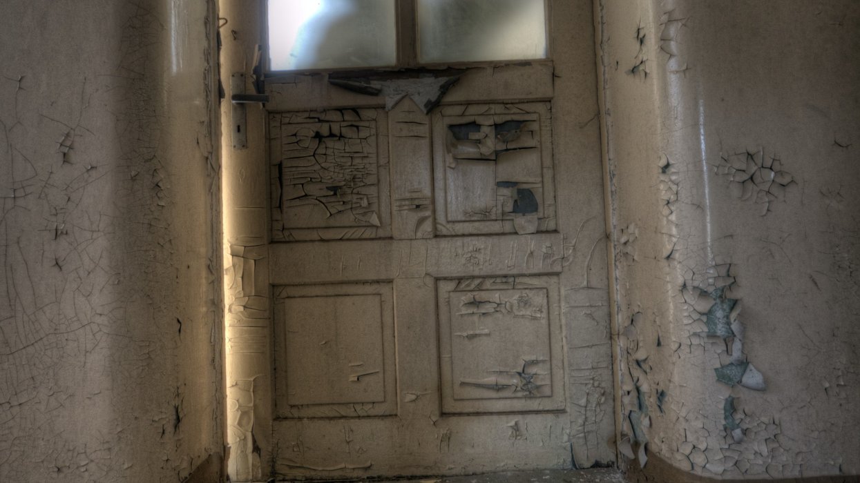 Silhouette of a person trying to break into a room through a frosted glass door.