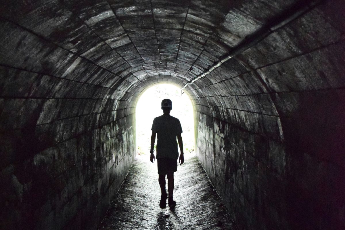 silhouette of person walking in tunnel