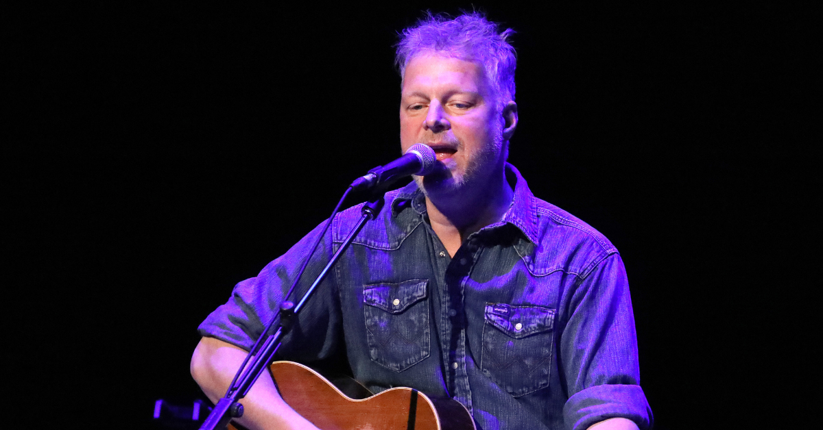 Singer Tal Bachman holding a guitar and singing on stage