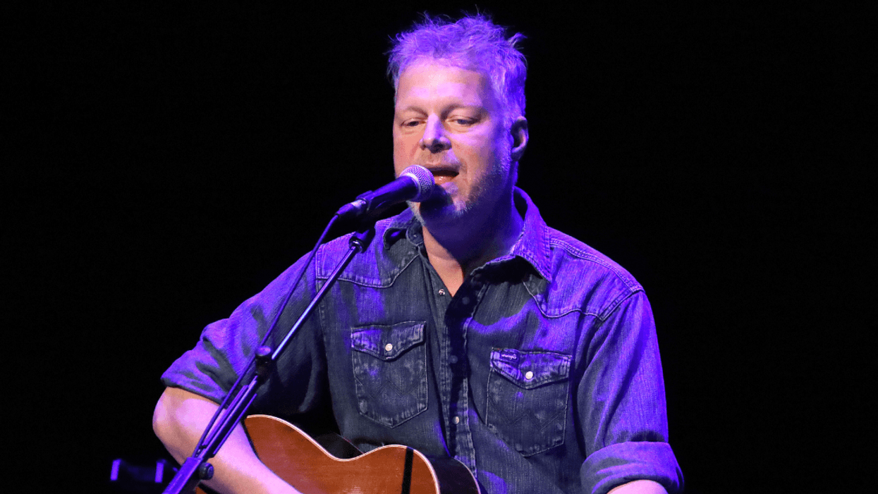 Singer Tal Bachman holding a guitar and singing on stage