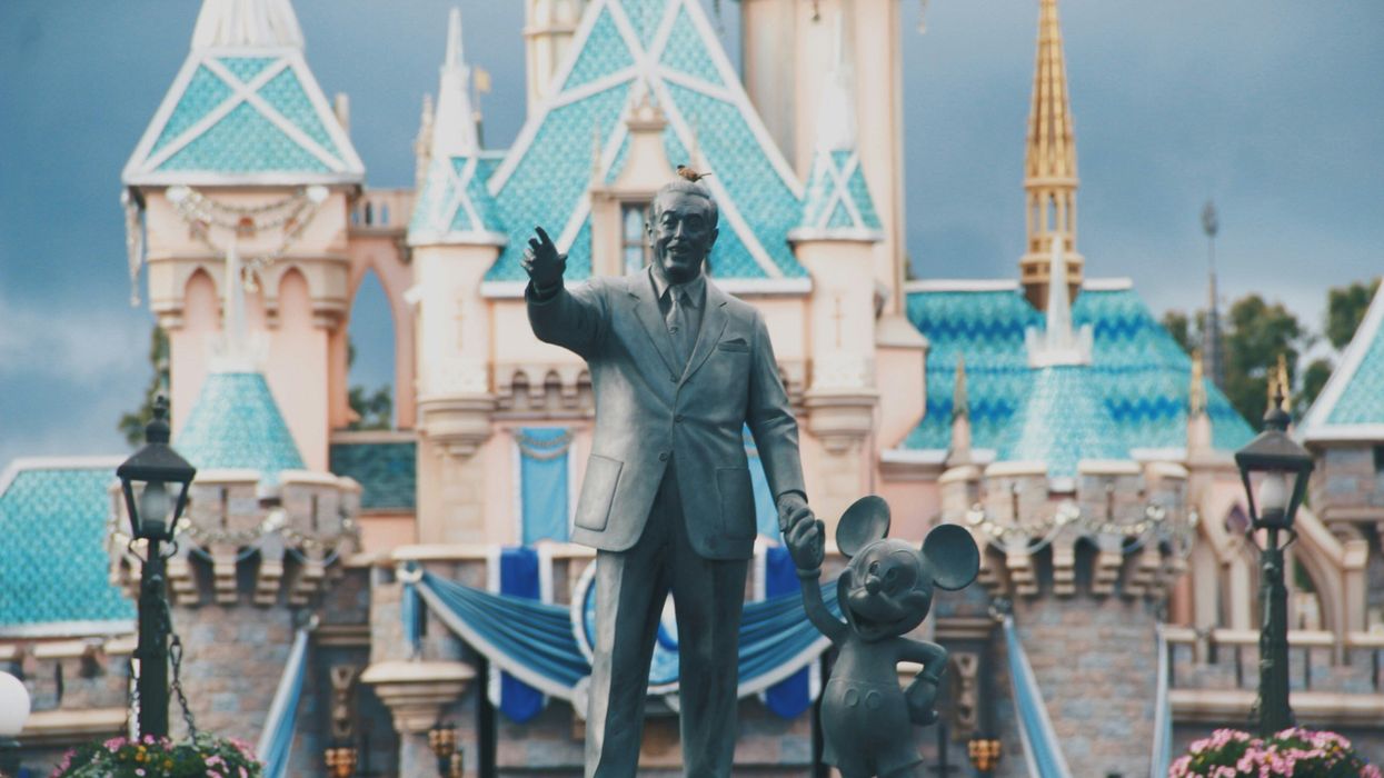 Statue of Walt Disney and Mickey Mouse in front of a castle
