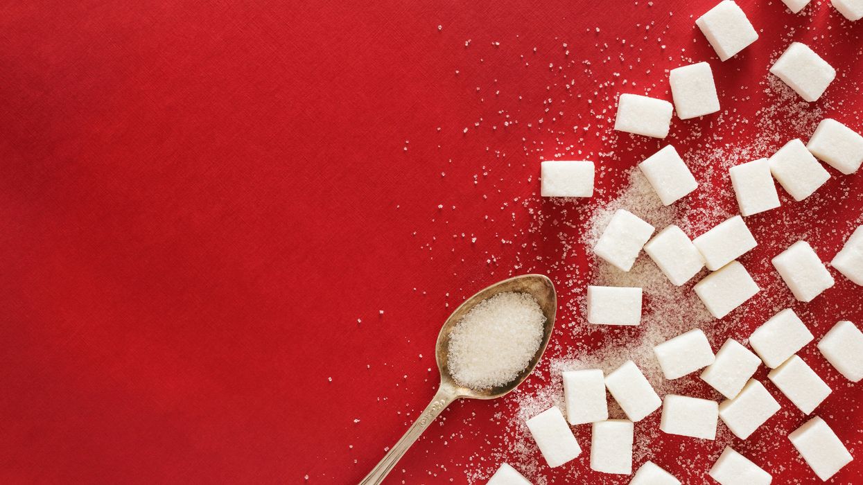 sugar cubes and a spoon on a red surface