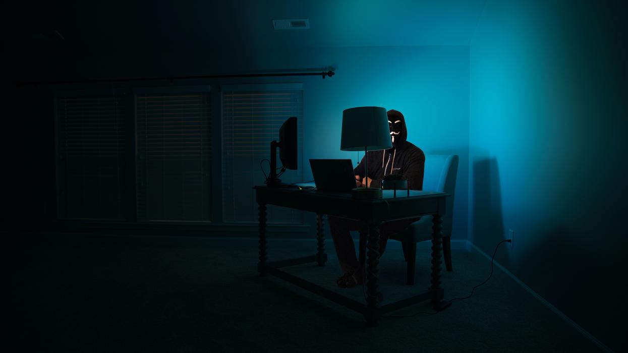 Suspicious person using computers in darkened room