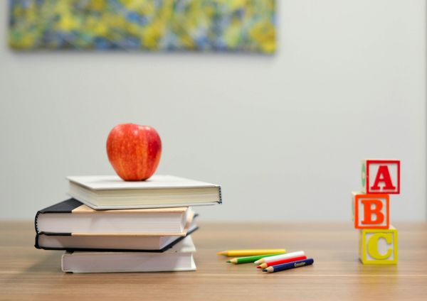 Teacher's desk with stack of books, apple, color pencils, and alphabet toy blocks