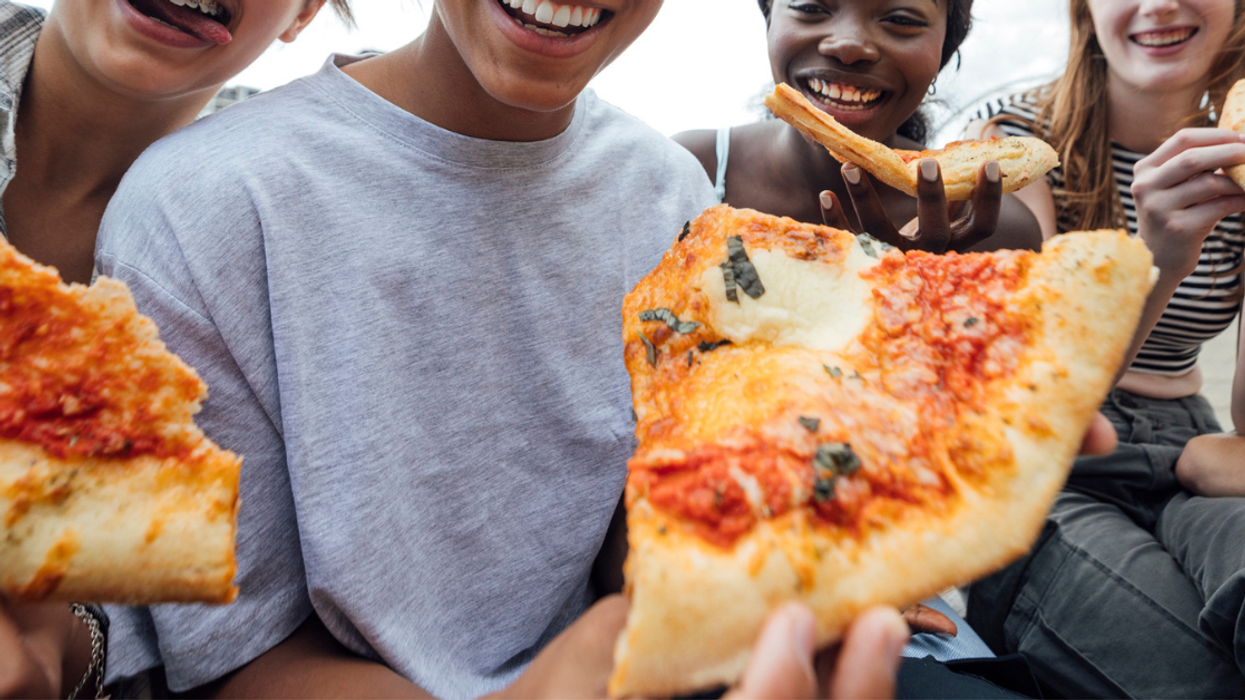 Teenagers eating slices of pizza