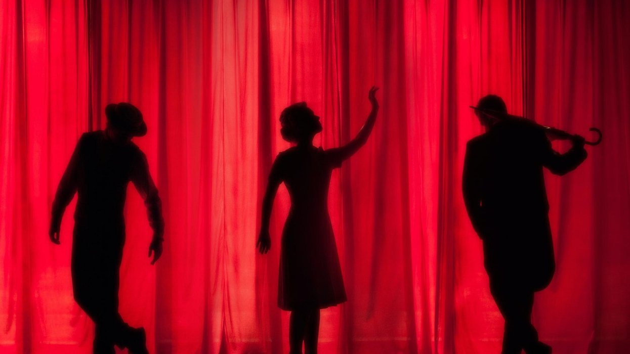 Three silhouettes of actors on a stage in front of a red curtain