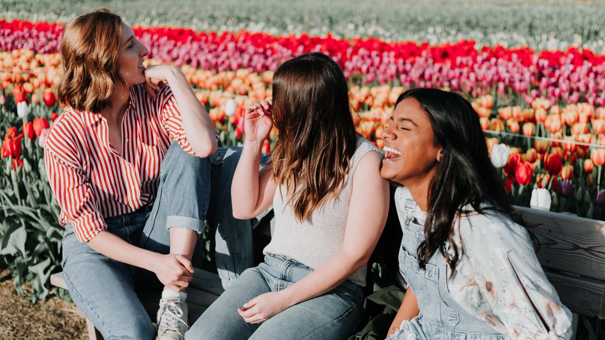 three women sitting wooden bench by the tulip flower field