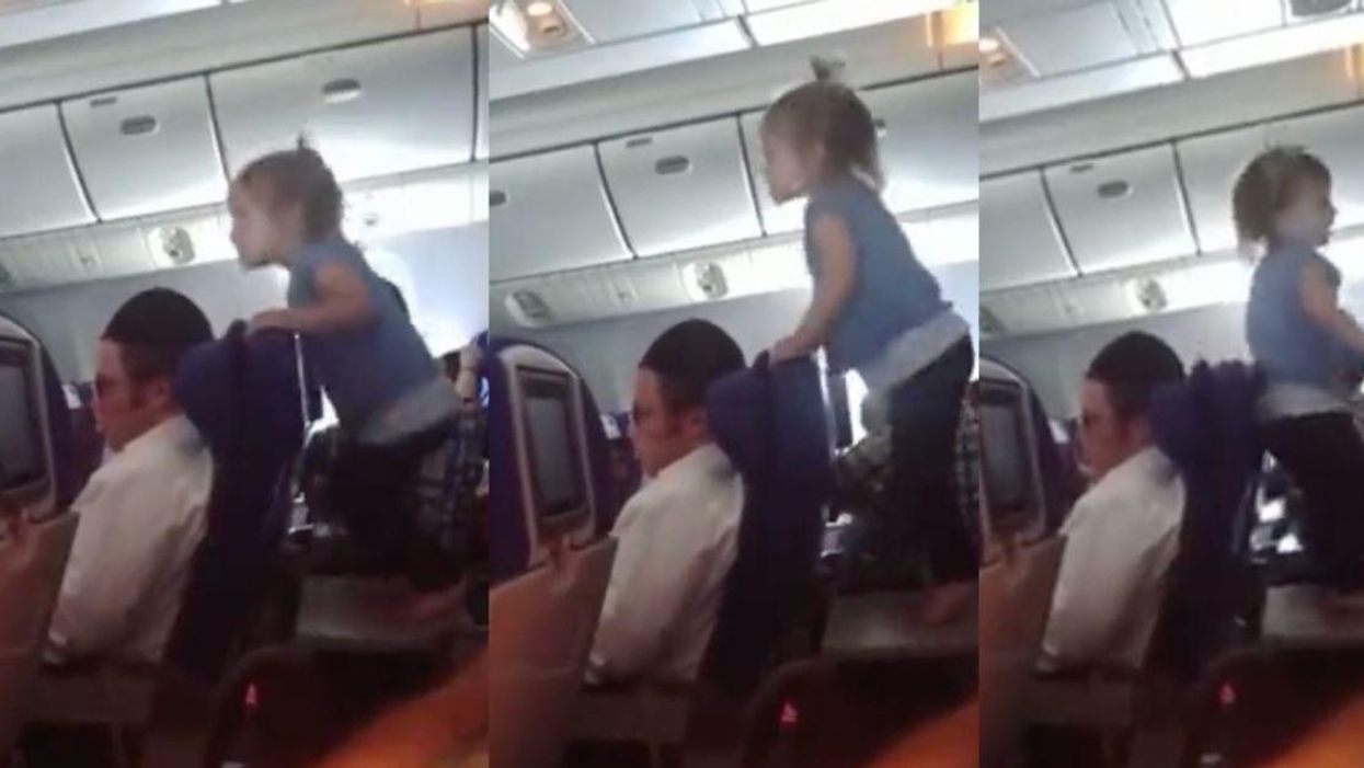 Toddler jumping on a tray table on an airplane.