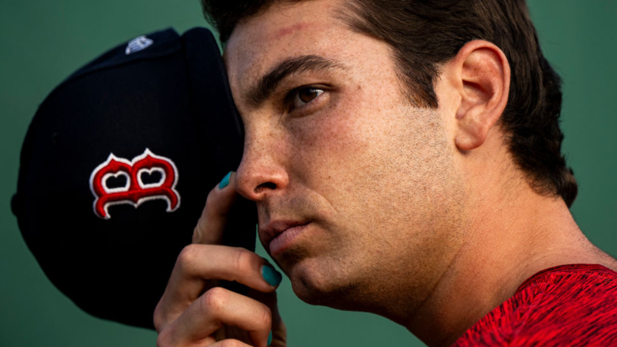 Triston Casas holding his baseball cap to his face and showing off his painted green nails.