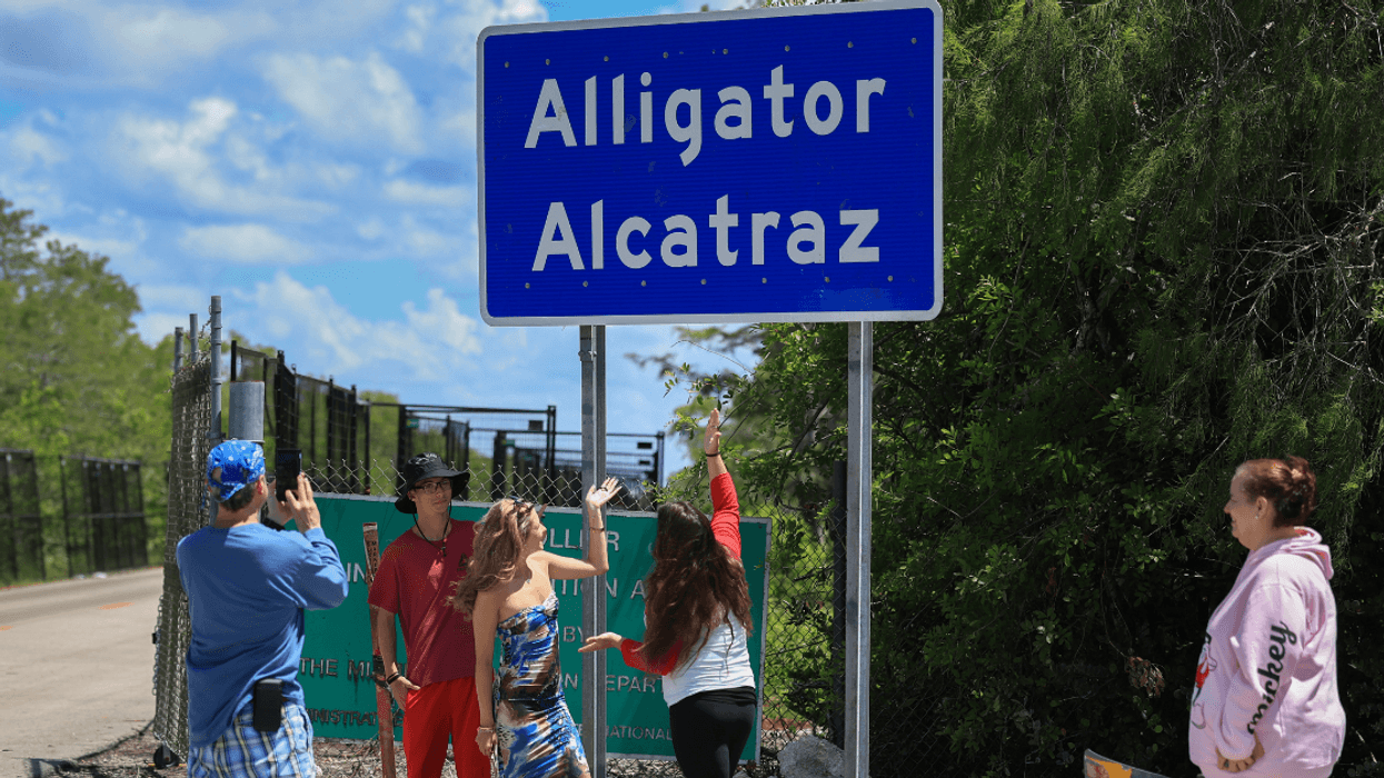 Trump fans take photos in front of the Alligator Alcatraz sign at the entrance of the immigrant detention facility