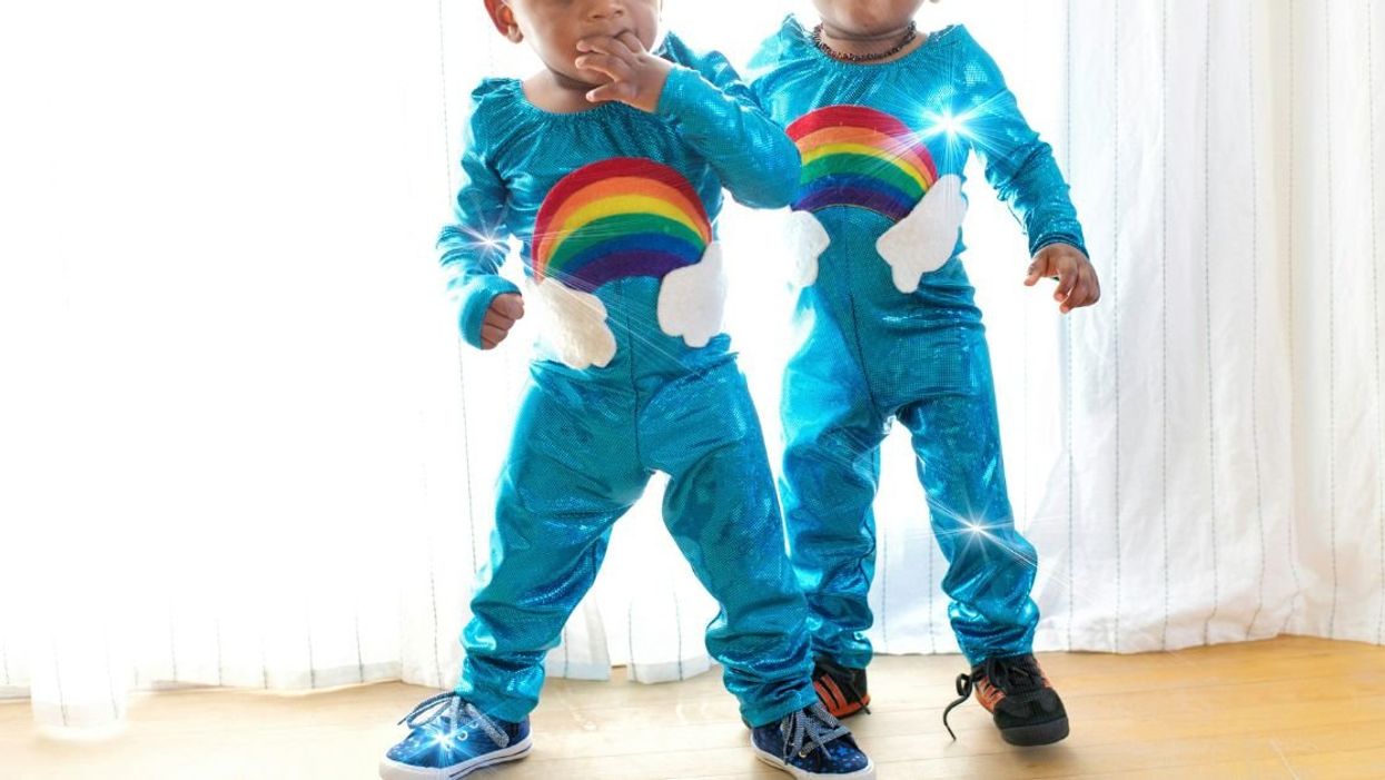 Twin toddlers in matching rainbow onesies