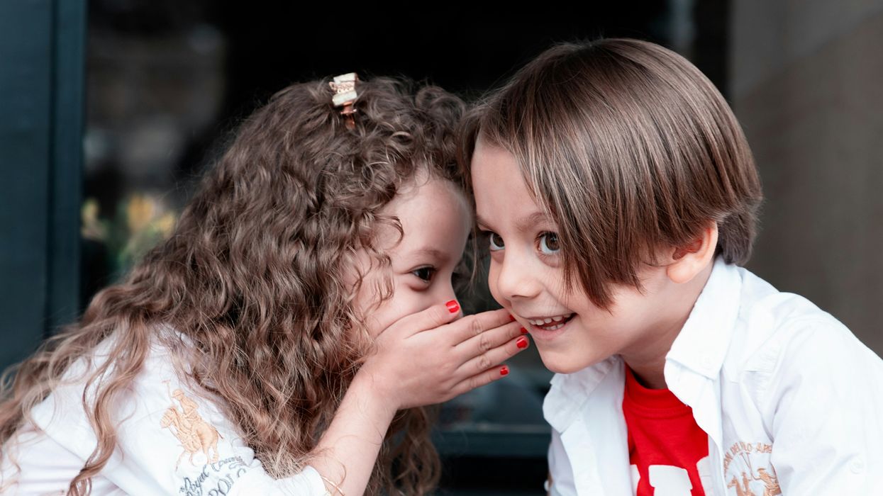 Two children whispering secrets to each other