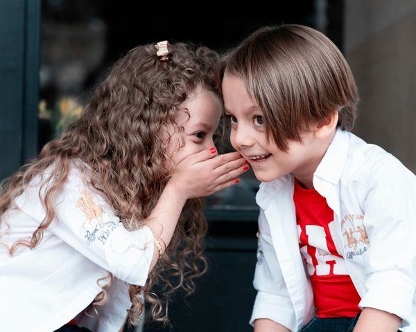Two children whispering secrets to each other