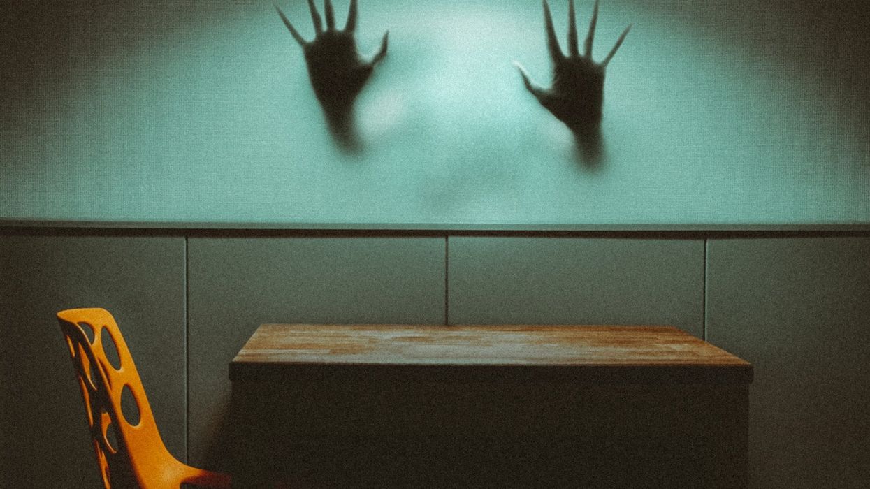 Two creepy, non-human hands come out of a mist and lay against glass