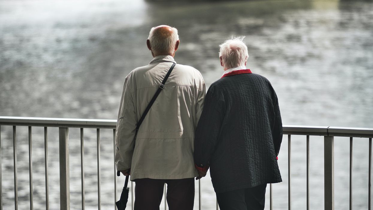 Two elderly people looking at the river from a bridge