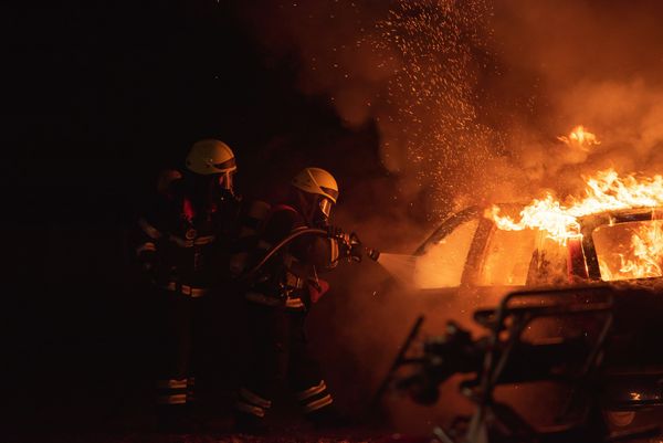 Two firefighters fighting a car fire
