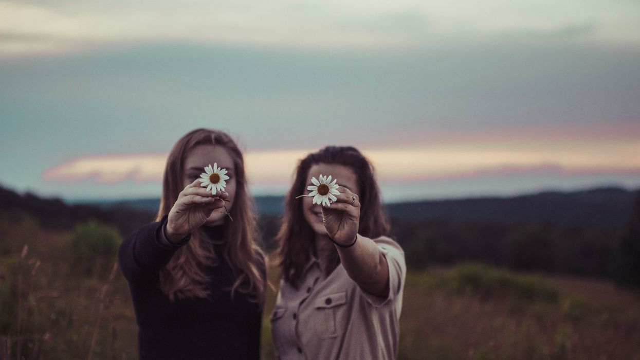 Two women holding up daisies