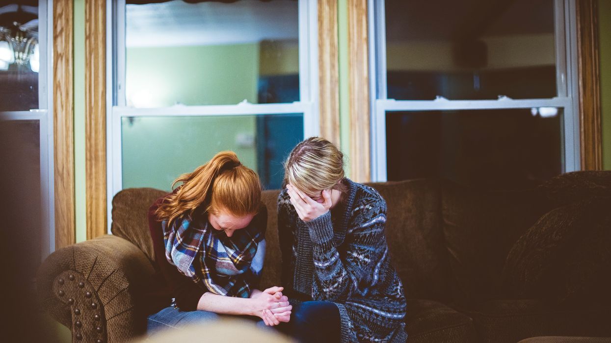 two women in emotional distress seated on couch