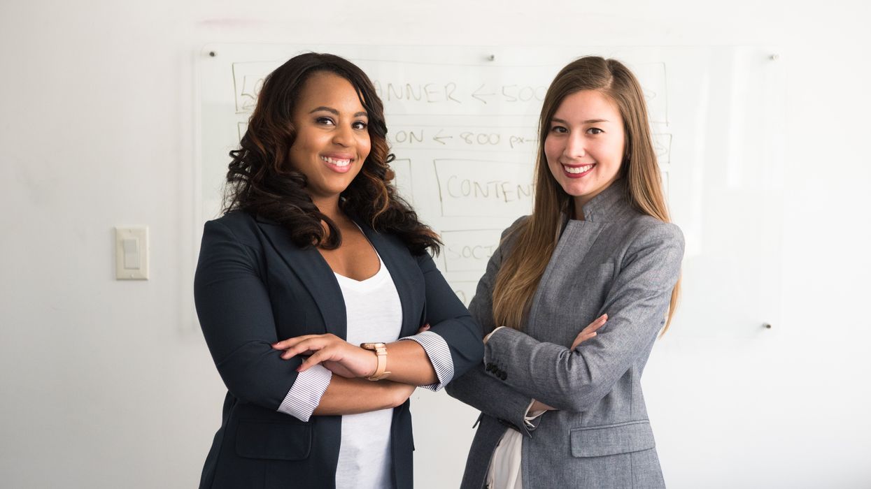 two women in suits standing beside wall