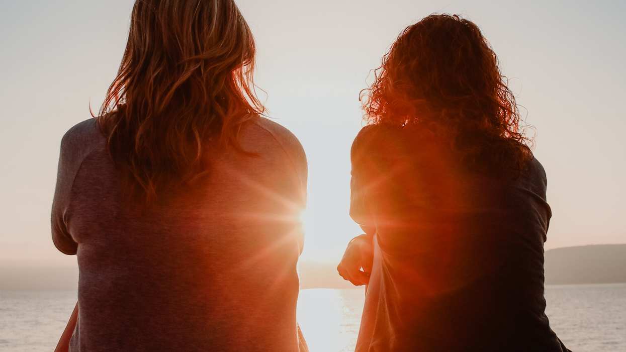 Two women looking on over a sunset