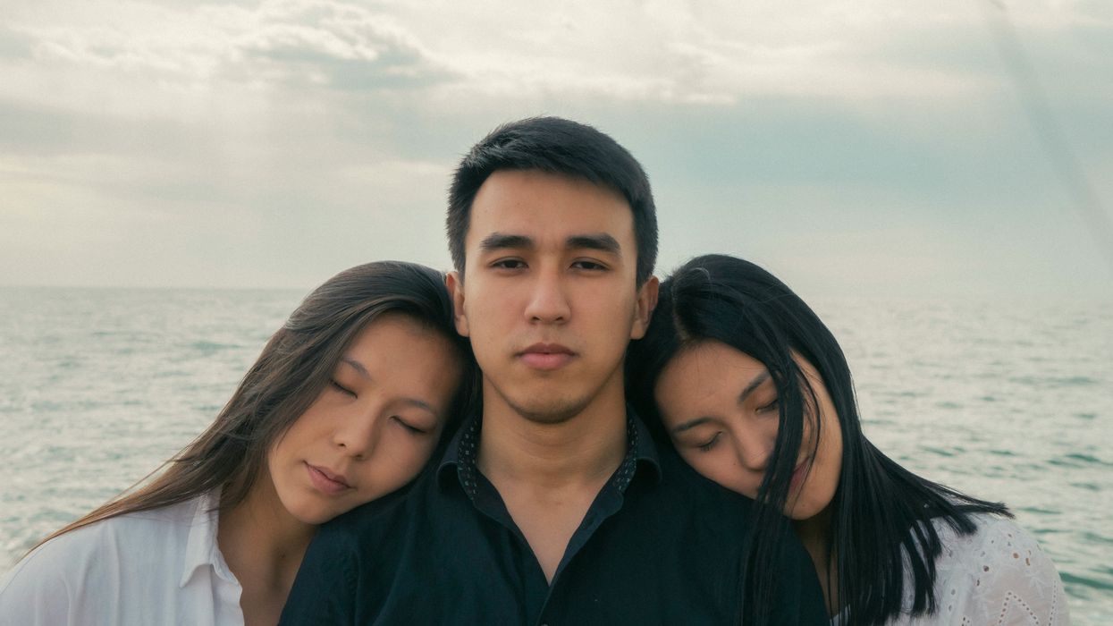 Two women resting their heads on a man's shoulders
