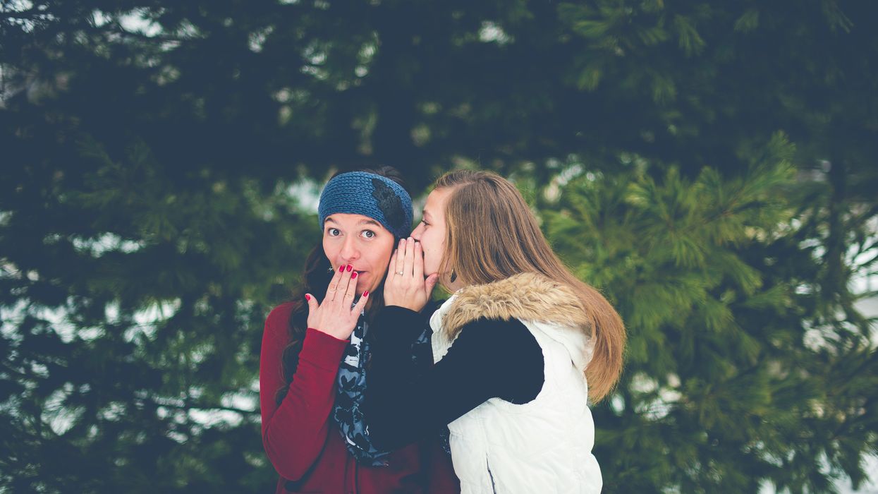 Two women whispering in each other's ears