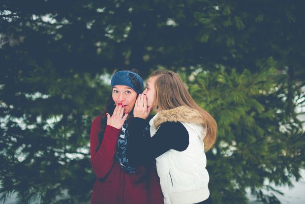 Two women whispering in each other's ears