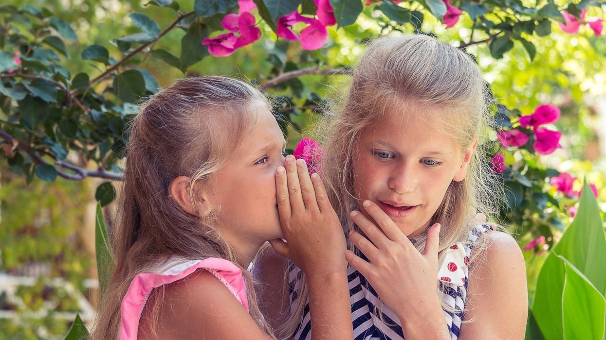 two young girls sharing a secret