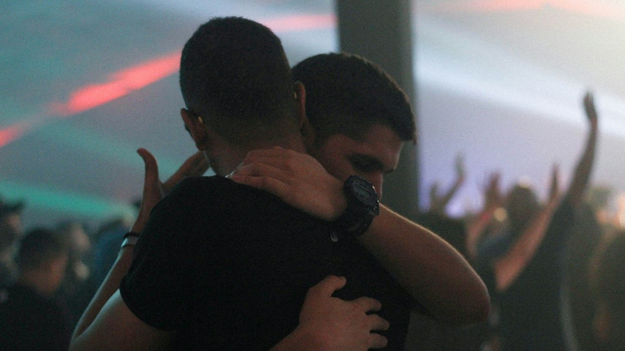 Two young men in a somewhat somber embrace.