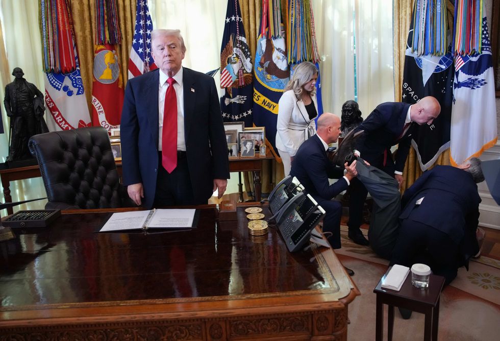 U.S. President Donald Trump stands by as attendees help a guest after he collapsed during during an event on lowering drug prices in the Oval Office at the White House on November 06, 2025 in Washington, DC. Trump announced that his administration has reached agreements with drugmakers Eli Lilly and Novo Nordisk that would lower the price of some GLP-1 weight loss medications.