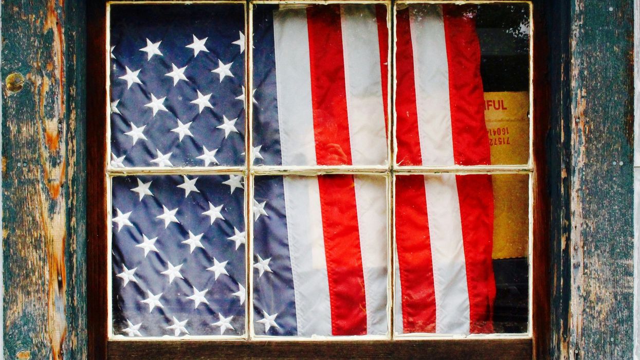 United States of America flag in window behind wooden pane