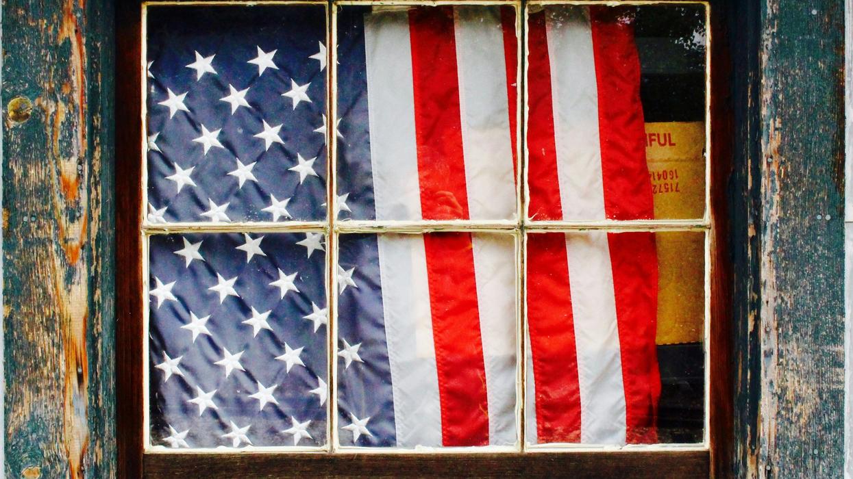 United States of America flag in window behind wooden pane