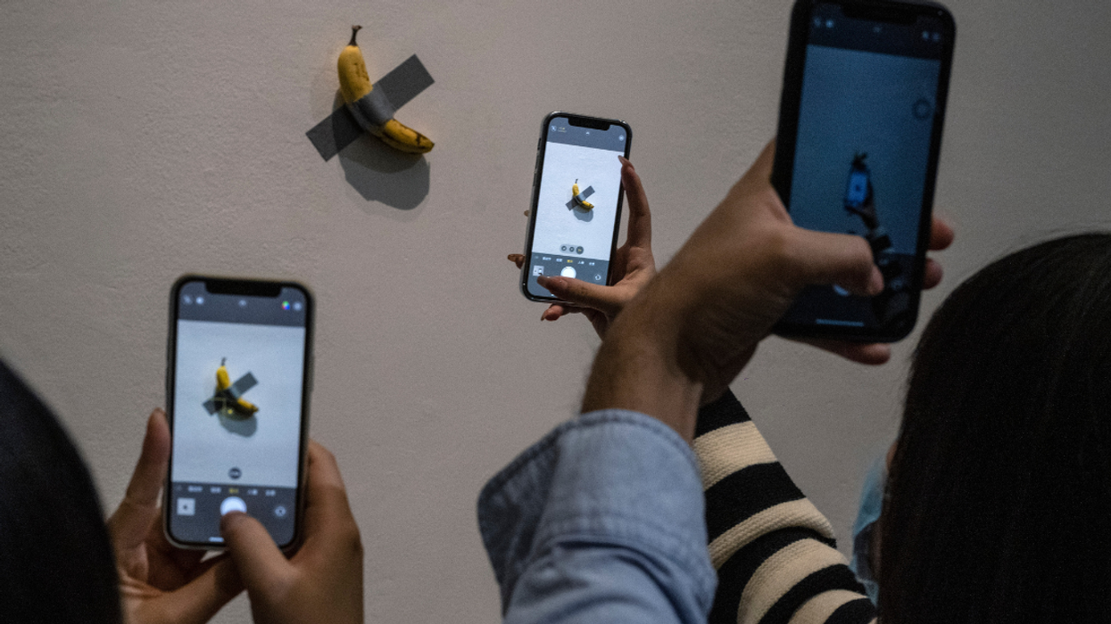 Visitors take pictures of the work "Comedian" by Italian artist Maurizio Cattelan that is part of his exhibition "The Last Judgement'' at the UCCA Center for Contemporary Art