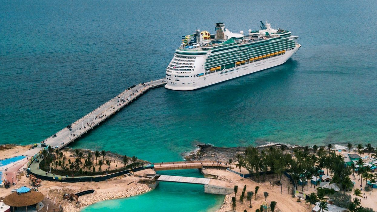 Wide shot of a cruise ship leaving an island stop.