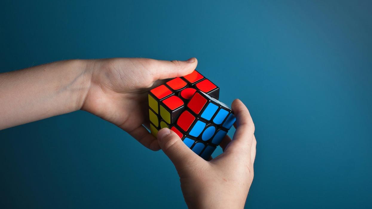 Wide shot of a young person's hands quickly solving a Rubik's cube.