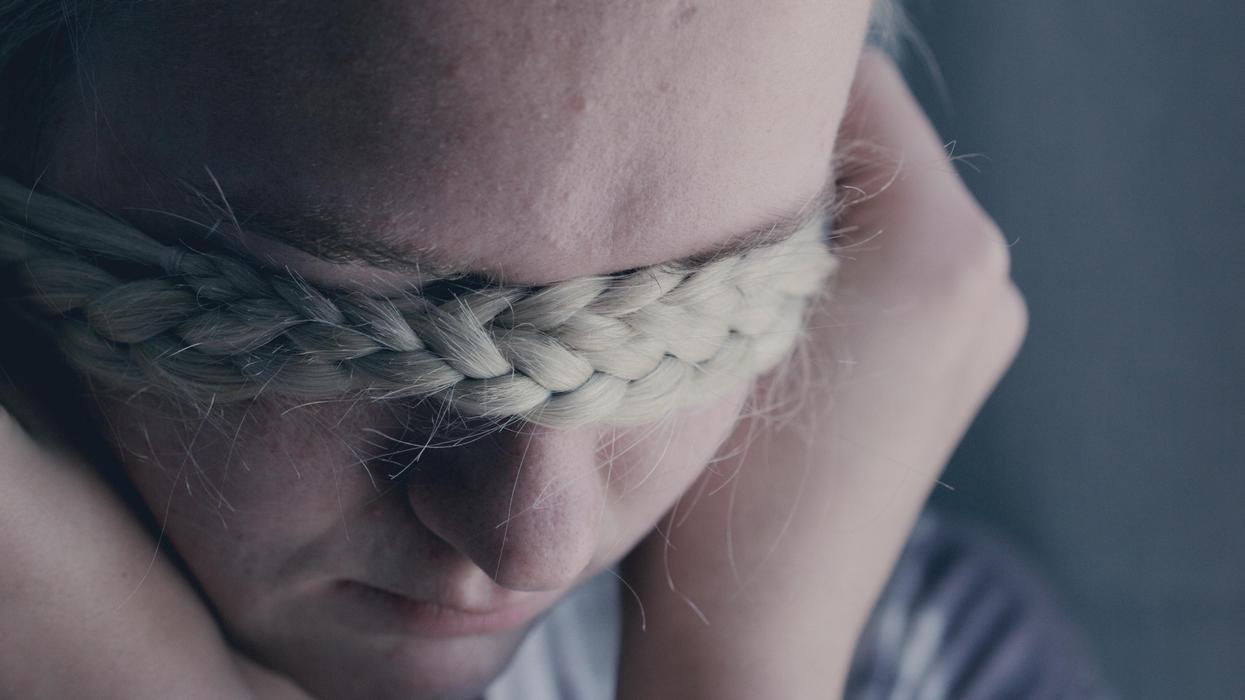 Woman covering eyes with braid