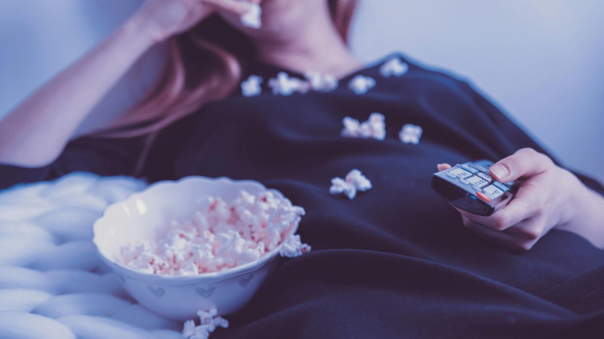 Woman eating popcorn watching TV at home