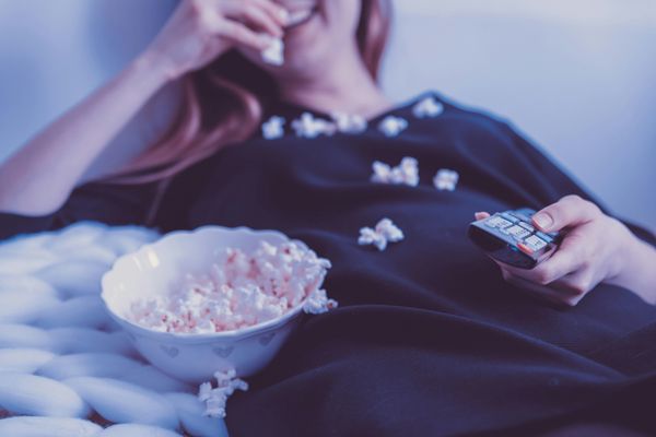 Woman eating popcorn watching TV at home