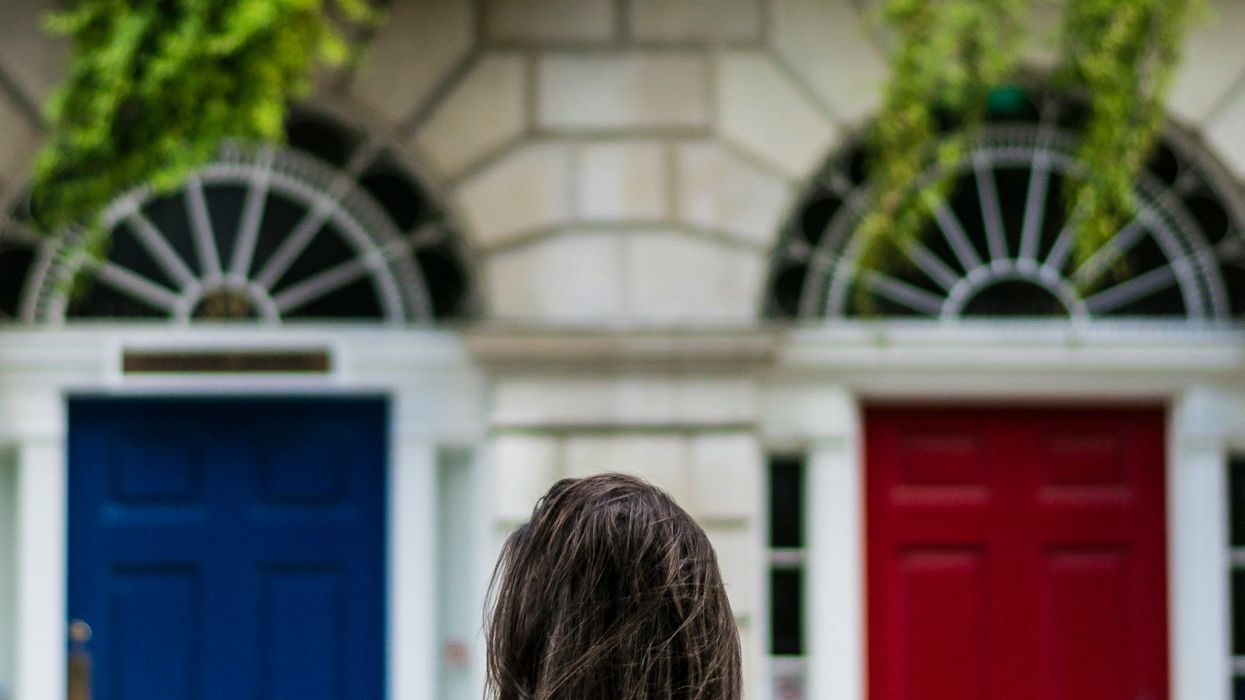 woman facing a blue door and a red door