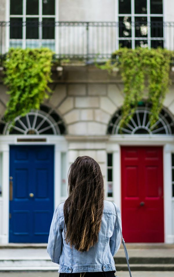 woman facing a blue door and a red door