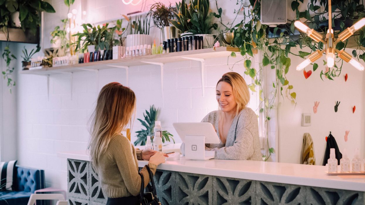 woman facing white counter making a purchase from female cashier