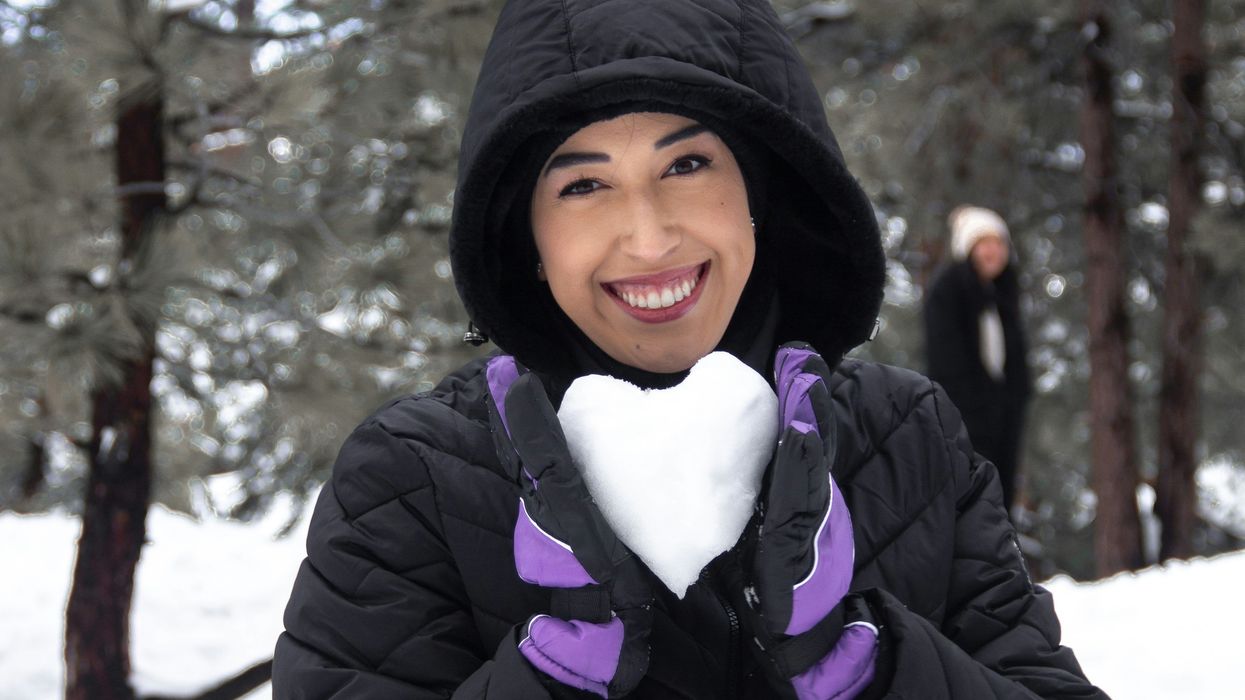 Woman holding a ball of snow shaped into a heart