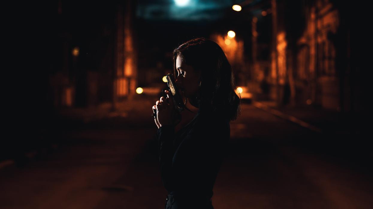 Woman holding a gun in the dark