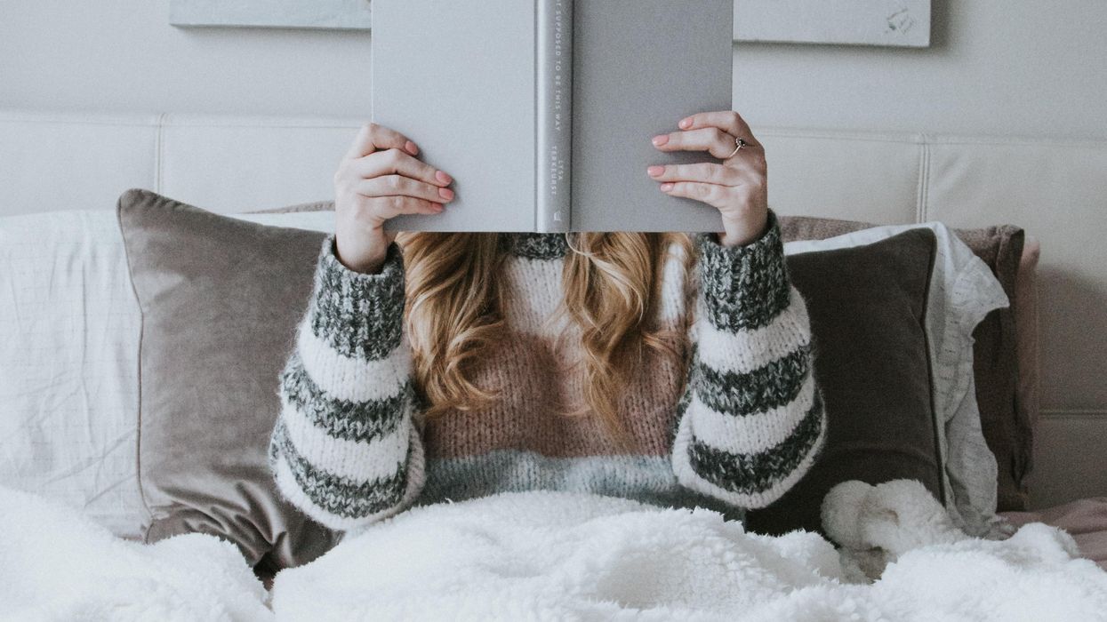 Woman holding book up in front of her face to read