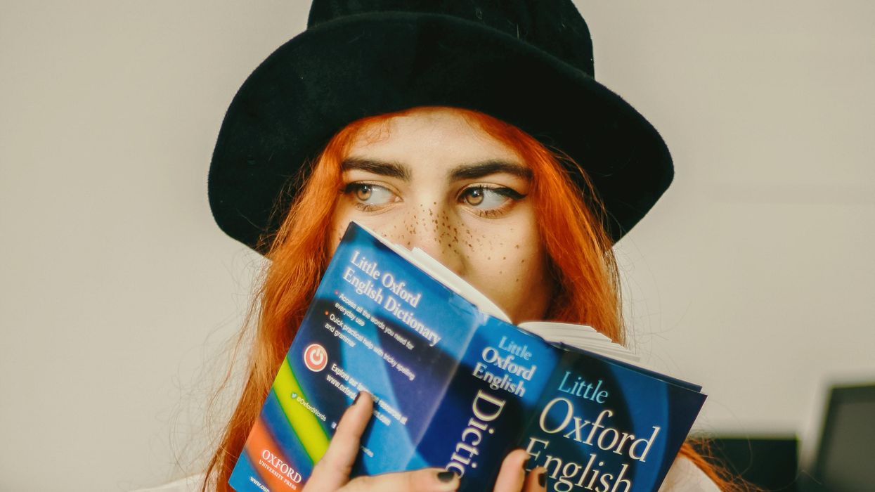 Woman holding up an Oxford English Dictionary
