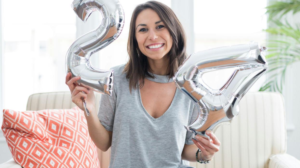 Woman holding up balloons to celebrate her 24th birthday