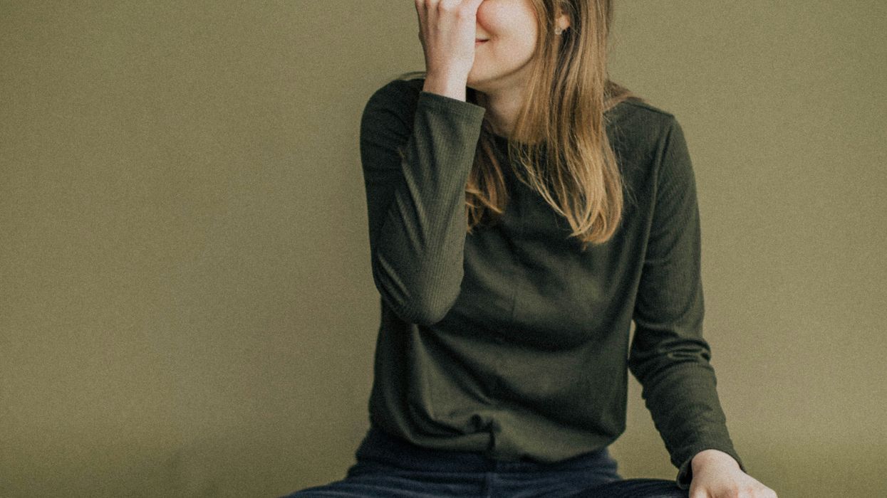 woman in green long sleeve shirt and blue denim jeans sitting on floor